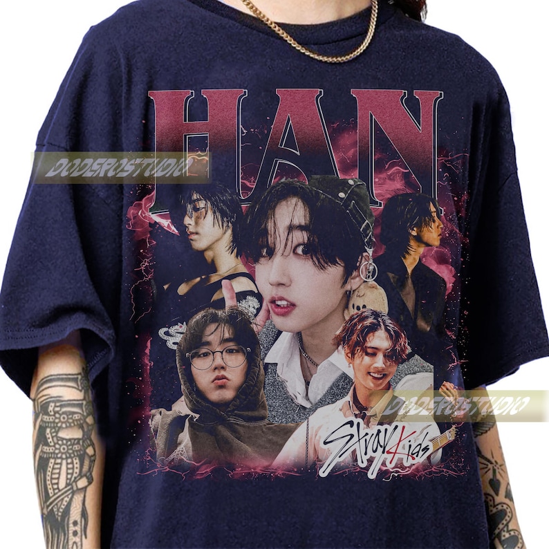 K&ouml;nnte beinhalten: Marineblaues T-Shirt mit einer Collage von Bildern eines Musikers. Der Name "HAN" ist oben in Burgunderrot gedruckt. Die Worte "Stray Kids" sind unten in wei&szlig;er Schrift gedruckt.