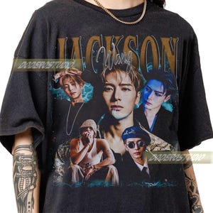 Könnte beinhalten: Dunkelgraues T-Shirt mit einer Collage von Bildern von Jackson Wang und dem Namen "JACKSON Wang" in goldfarbenen Buchstaben. Das Design umfasst Blitzakzente und mehrere Porträts des Künstlers.