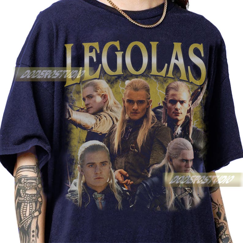 Pu&ograve; includere: T-shirt blu navy con una grafica di Legolas de Il Signore degli Anelli. Il design include pi&ugrave; immagini del personaggio con il nome "LEGOLAS" in oro, in stile vintage. Lo sfondo ha un effetto fulmine giallo.