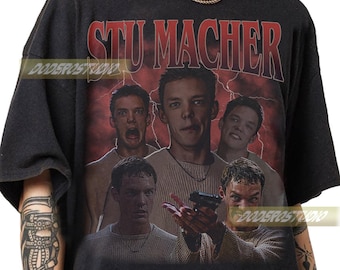 May include: Black t-shirt featuring a graphic of Stu Macher with multiple images of his face and the text "STU MACHER" in red. The background has a red lightning bolt design.