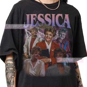 May include: Black t-shirt featuring a graphic of Jessica Fletcher from the television show "Murder, She Wrote." The design includes the name "JESSICA" in a retro font, with "Fletcher" underneath. The image shows multiple portraits of the character.