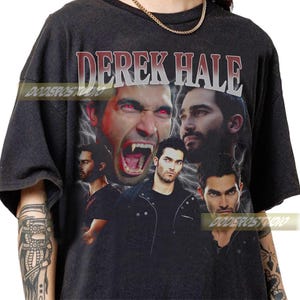 May include: Dark gray t-shirt featuring a collage of images of Derek Hale with the text "DEREK HALE" in a distressed font. The design includes images of the character with red eyes and fangs, and other portraits. The shirt has a vintage style.