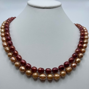 May include: A double strand pearl necklace with graduated pearls. The pearls are a mix of peach and burgundy colors.
