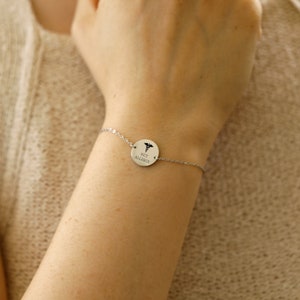May include: A silver bracelet with a round charm that says "Nut Allergy" and has a medical symbol on it.