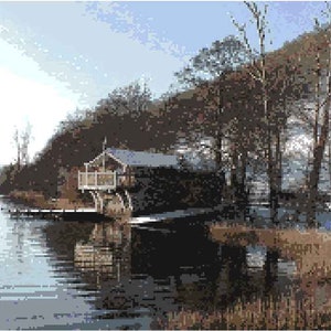 May include: A wooden cabin with a deck overlooking a lake. The cabin has a grey roof and white trim. The lake is calm and reflects the sky and trees.