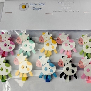 Puede incluir: Un paquete de 10 mini pinzas de madera con forma de vaca en varios colores. Cada pinza presenta un diseño de vaca con cabeza blanca y cuerpo colorido. Las pinzas miden aproximadamente 35 mm y son ideales para manualidades.