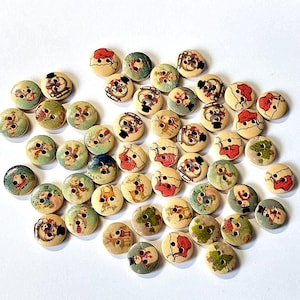 May include: A collection of round wooden buttons with festive holiday designs. The buttons feature illustrations of snowmen, Christmas trees, and other winter-themed images in red, green, and blue on a light beige background.