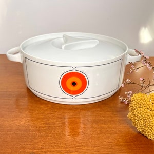 May include: White ceramic serving dish with a lid. The dish features a black and white geometric design with a large orange circle in the centre.