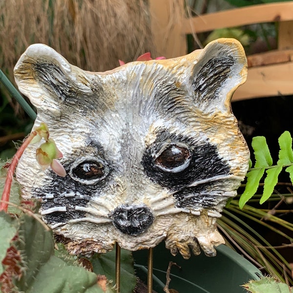 Cement, Raccoon garden ornament. Hand sculpted and painted. 4" by 4 1/2". Sturdy brass rods stand in the soil. Sealed with waterproof spray.