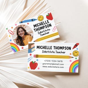 May include: Two business cards with a school theme. The cards feature the name "Michelle Thompson, Substitute Teacher" with a photo, a rainbow, a pencil, and other school-related graphics. Contact information is also included.