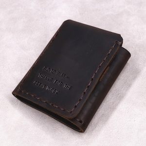 以下が含まれることがあります： ステッチされたエッジを備えた濃い茶色の革の財布。財布は折り畳み式のデザインで、「S.O.TO W.M. - THANKS FOR THE GREAT WORK」とエンボス加工されたテキストが特徴です。