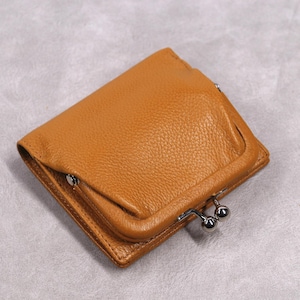 May include: A tan leather wallet with a kiss-lock clasp. The rectangular wallet has a textured surface and a small flap. The metal clasp is silver-coloured.