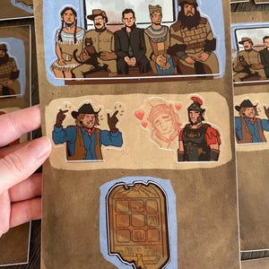 May include: A set of six stickers featuring cartoon characters in various poses. The stickers are printed on a brown background with a light blue border. The characters include a cowboy, a Roman soldier, a man with a beard, and a woman with long black hair. The stickers are perfect for adding a touch of whimsy to your laptop, water bottle, or planner.