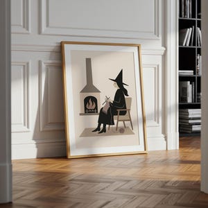 Op de afbeelding: Ingelijste kunstdruk met een heks die bij een open haard breit. De illustratie heeft een minimalistische stijl met een neutraal kleurenpalet. De heks draagt een zwarte hoed en jurk, zittend in een stoel. De open haard heeft een grijze schoorsteen en een vuur.