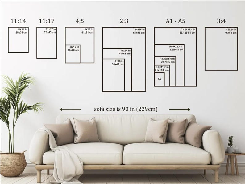 May include: A wall with various rectangular black frames displaying different aspect ratios and sizes, including 11x14 in (28x36 cm), 16x20 in (41x51 cm), and 24x36 in (61x91 cm). The text "sofa size is 90 in (229cm)" is below the frames.