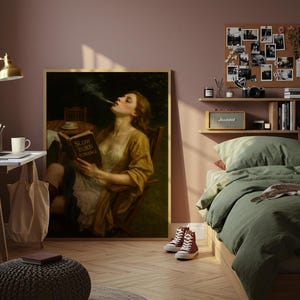 May include: A large framed artwork shows a woman reading a book titled "Slow Burn Romance" and smoking. The room includes a desk with a laptop, a bed with green bedding, and a corkboard displaying photographs.