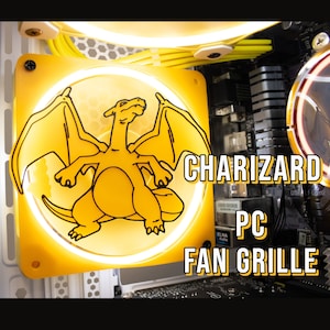 May include: A yellow computer fan grille with a black outline of a Charizard Pokemon. The text "CHARIZARD PC FAN GRILLE" is printed on the grille.