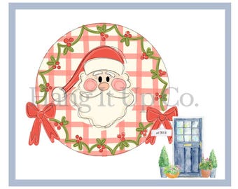 May include: A watercolor illustration featuring Santa Claus within a red and white plaid circle, adorned with a green garland and red bows. A blue door with potted plants is at the bottom. The text "Hang it up Co." is visible.