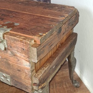 May include: A wooden box with metal hardware and decorative cast iron legs. The box is made of reclaimed wood and has a rustic look.