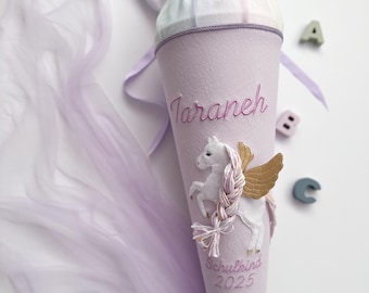 May include: A purple school cone with a unicorn design, the name "Taranch" embroidered on the cone, and the text "Schulkend 2025" embroidered below the unicorn. The cone is decorated with a white tulle bow.