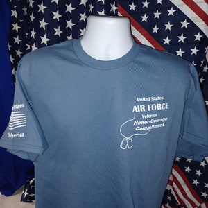 May include: A blue t-shirt with a white graphic of a dog tag necklace with the text "United States Air Force Veteran Honor-Courage Commitment".