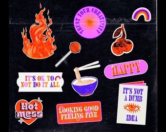 May include: A collection of colorful stickers with various designs and text on a black background. Designs include a flame, a lollipop, a bowl of noodles, a rainbow, cherries, and the words "HAPPY", "Hot mess", "Looking good feeling fine", "It's not a dumb idea", and "Trust your creativity".
