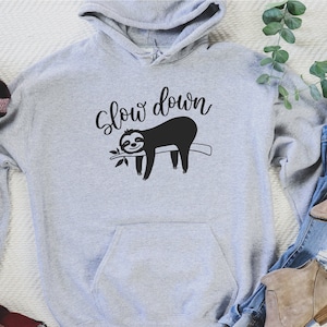 May include: Gray hooded sweatshirt with a black sloth graphic and the text "Slow down".