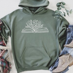 May include: A green hooded sweatshirt with a white outline of an open book with flowers growing from it.