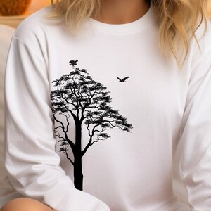 May include: White long-sleeve shirt with a black silhouette of a tree and birds on the front.