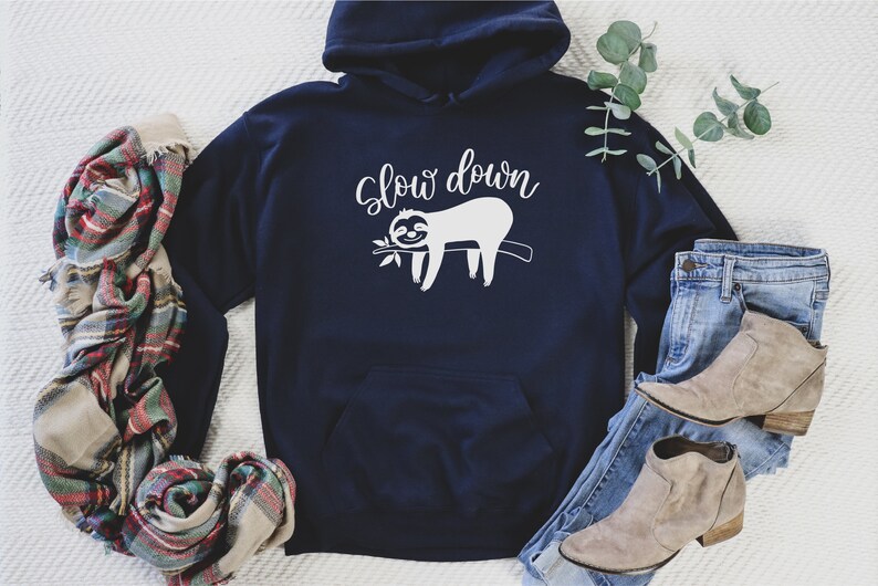 May include: A navy blue hoodie with a white graphic of a sloth hanging on a branch with the text "Slow down".