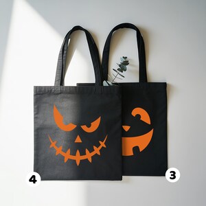 two black tote bags with Halloween-themed orange designs on them.