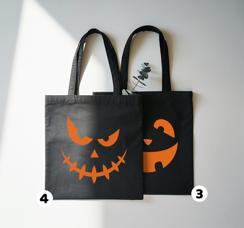 two black tote bags with Halloween-themed orange designs on them.