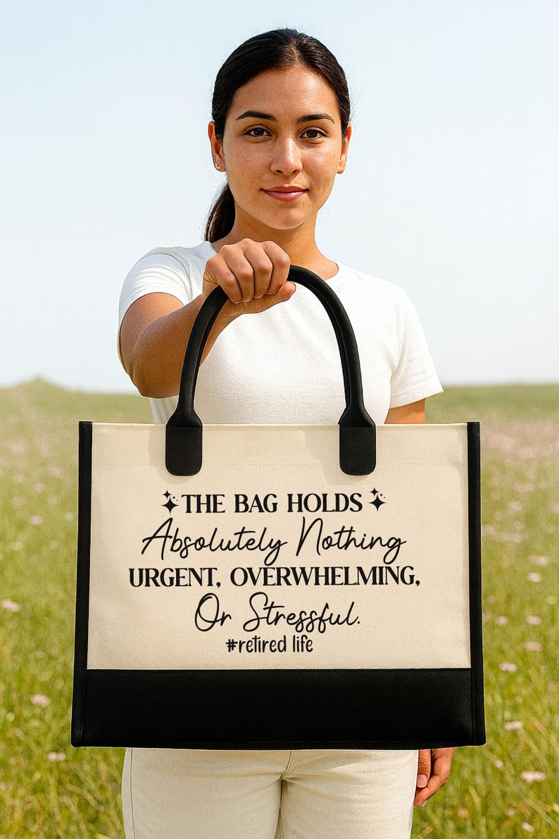 A woman holding a large tote bag with text on it, standing in a field with a clear blue sky in the background.