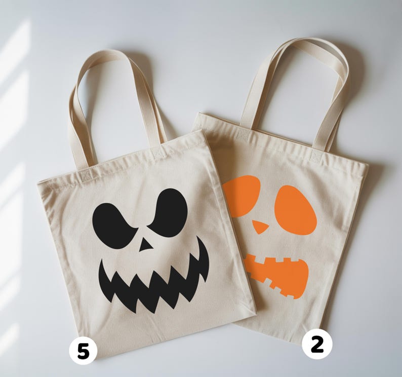 two tote bags with Halloween-themed designs, including a white bag with a black jack-o-lantern face and an orange bag with a similar face.