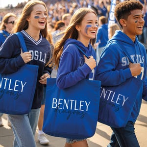 A group of people wearing blue shirts and carrying blue bags with the word "BENTLEY" printed on them, walking together in a crowd.