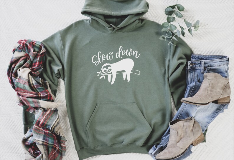 May include: A green hooded sweatshirt with a white graphic of a sloth on a branch and the text "Slow down".