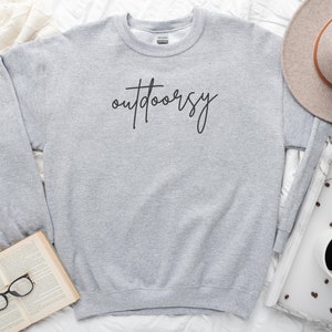 May include: A gray sweatshirt with the word "outdoorsy" written in black cursive on the front.