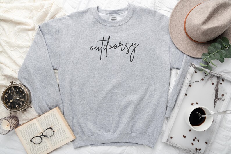 May include: A gray sweatshirt with the word "outdoorsy" written in black cursive on the front.