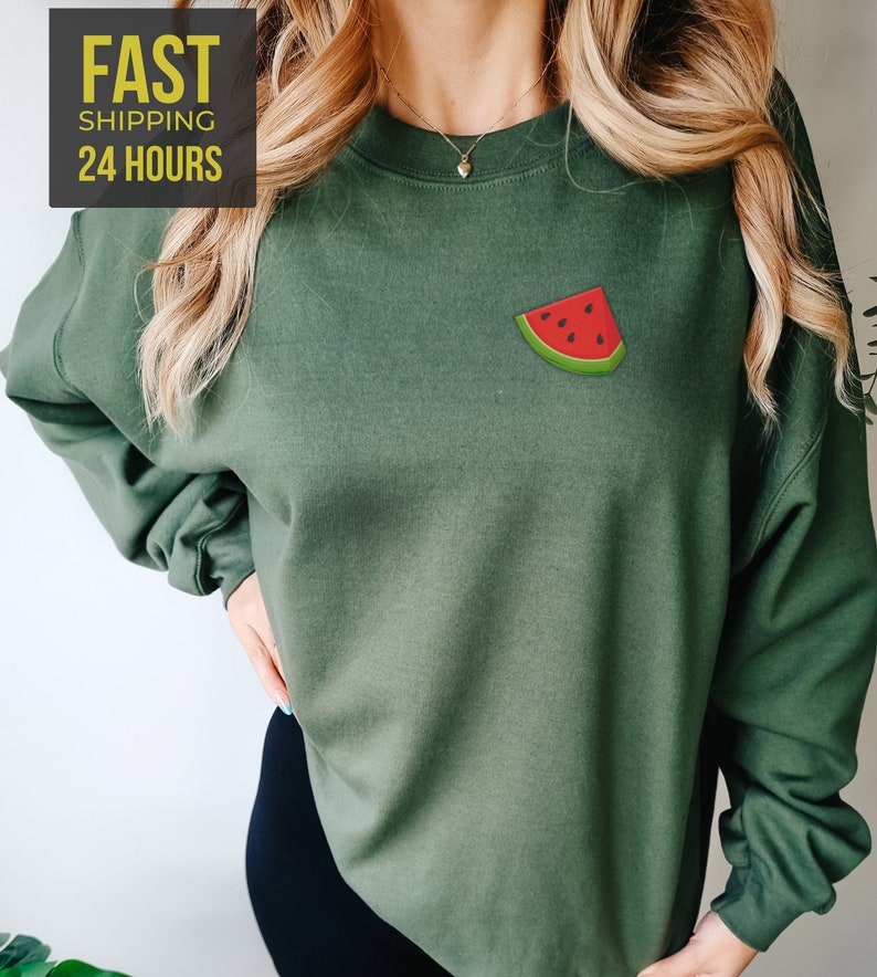 Op de afbeelding: Een groen sweatshirt met een watermeloenprint op de voorkant. Het sweatshirt heeft lange mouwen en een ronde hals.