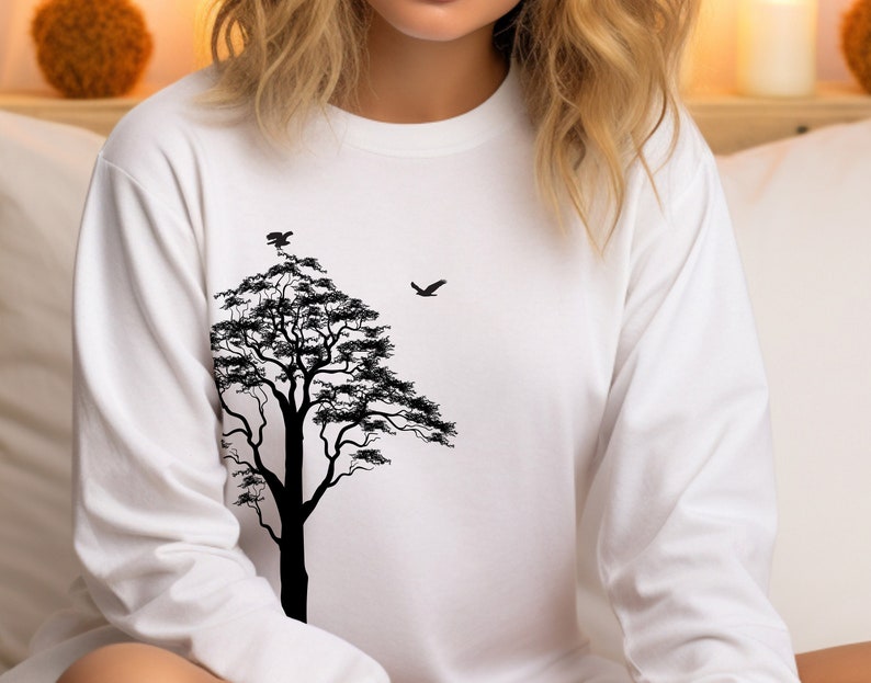 May include: White long-sleeve shirt with a black silhouette of a tree and birds on the front.