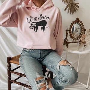 May include: A pink hoodie with a black sloth graphic and the text "Slow down".