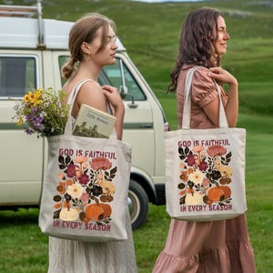 Two women standing in a grassy field, each carrying a tote bag with a floral design and text.
