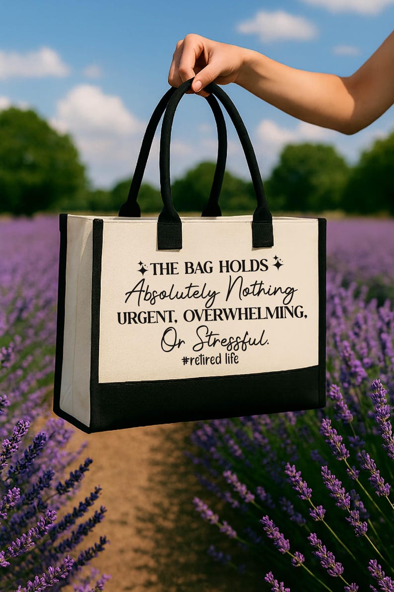 A hand holding a bag with text printed on it, standing in front of a field of purple flowers.
