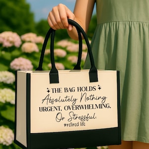 A person is holding a bag with a humorous text printed on it, standing in front of a field of flowers.