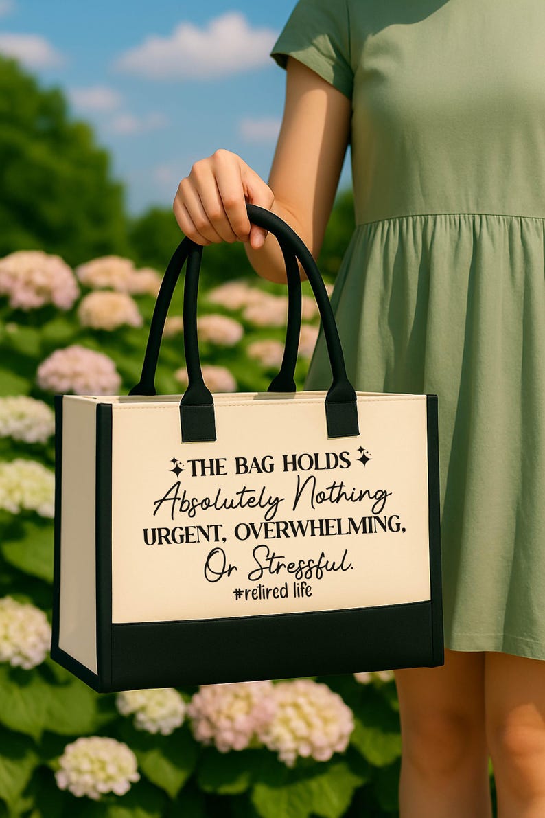 A person is holding a bag with a humorous text printed on it, standing in front of a field of flowers.