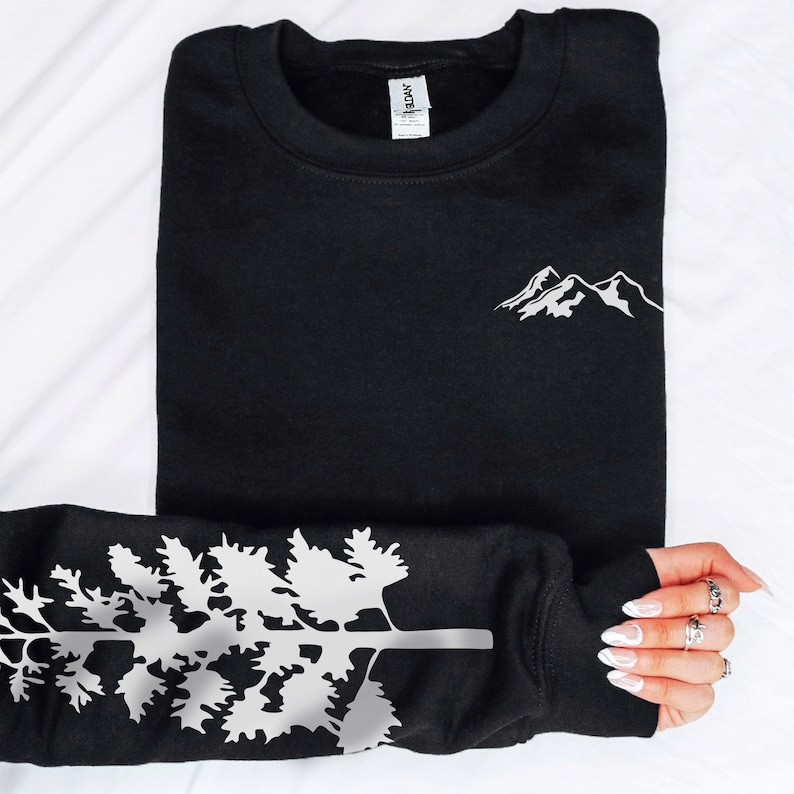 May include: Black sweatshirt with a white mountain graphic on the front and a white tree graphic on the sleeve.