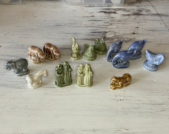 May include: A collection of 12 miniature figurines, including a donkey, a camel, a lamb, a rooster, a goose, a cow, a sheep, a bird, and three figures in robes. The figurines are made of ceramic and are painted in various shades of brown, gray, white, blue, and green.