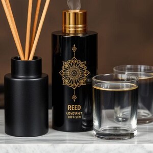 May include: A black reed diffuser set with a gold-accented bottle, a matching black container with reeds, and two clear glasses with gold rims. The diffuser bottle has a gold floral design and the text "REED LONDONY DIFFUSER".