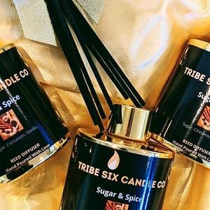 May include: Three black reed diffusers with gold lids and accents. The bottles are labelled "TRIBE SIX CANDLE CO" with "Sugar & Spice" and a graphic. The reed diffuser is hand-poured with love.