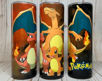 May include: Three cylindrical tumblers featuring Pokemon characters. The designs include Charizard, Charmander, and Charmeleon, set against a fiery orange and black background. The word "Pokemon" is displayed on one tumbler.